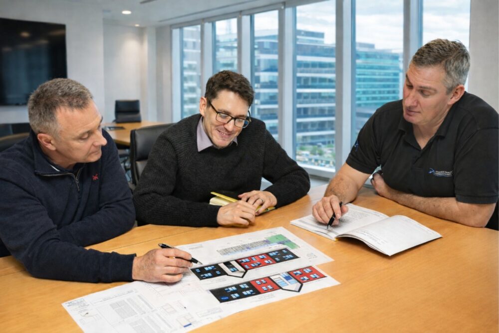 Staff looking at plans and drawings on a meeting room table